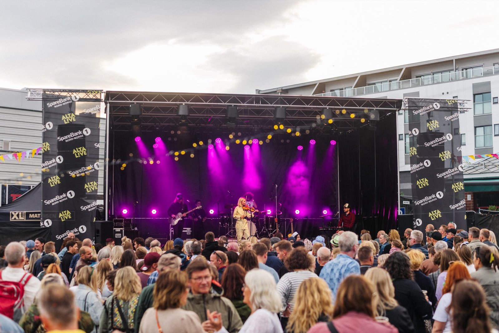 Utendørs scene i Alta med rosa scenelys og publikum foran